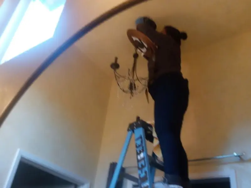 Electrician installing a chandelier in a Canton residence